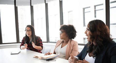 A group of women sitting at a table talking.