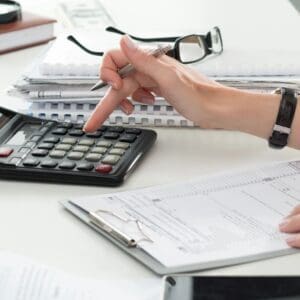 A person is working on some papers and a calculator