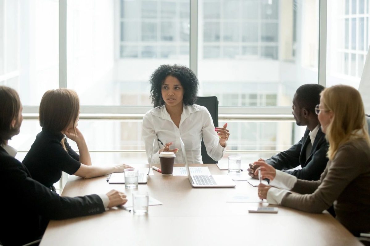 A group of people sitting at a table in front of a window.